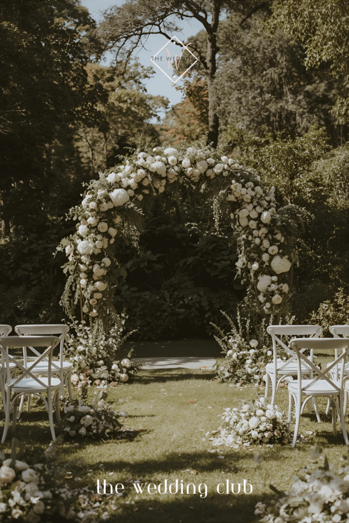 Romantic outdoor wedding arch with white roses and greenery — ceremony décor ideas for brides.