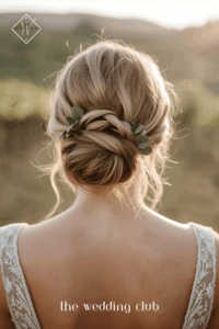 Low knot bun with greenery accents tucked in, champagne dress, rustic vineyard wedding background